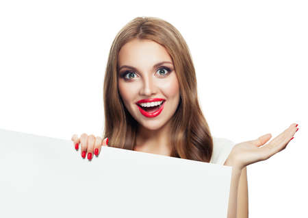 Happy surprised model woman showing open hand and holding white empty paper signboard isolated on white backgroundの写真素材