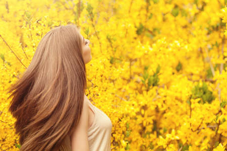 Romantic portrait of beautiful woman with long blowing hair on floral backgroundの写真素材
