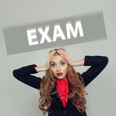 Scared student woman with exam inscriptionの写真素材
