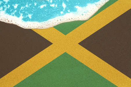 Sea wave on the sunny sandy beach with flag Jamaica. View from top on surf.の写真素材