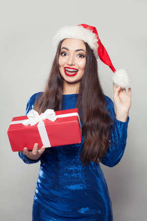 Beautiful Santa woman in braces holding Christmas giftの写真素材