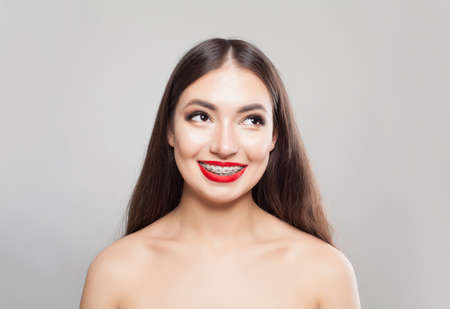 Pretty woman in braces smiling on whiteの写真素材