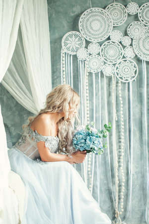 Perfect beauty woman with blonde curly hair and flowers in vintage interiorの写真素材