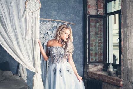 Perfect blonde woman in blue lacy dress at vintage homeの写真素材