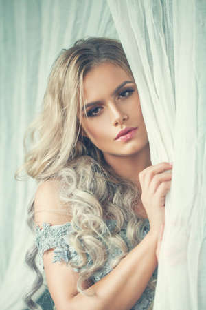 Pretty woman with blonde hair on white vintage fabricの写真素材
