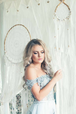 Portrait of young beauty woman with blonde curly hair at home. Romantic locationの写真素材