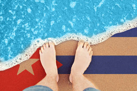 Two feet on sandy beach with flag Cuba. Top View on surf.の写真素材
