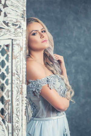 Beautiful young woman posing luxurious interior. Vintage romantic portrait of blonde girlの写真素材