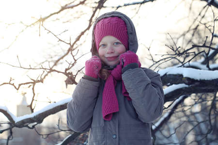 Young Girl in Pink Hat and Scarf in Park in Snowy Winter Day. Child Girl Outdoorsの写真素材