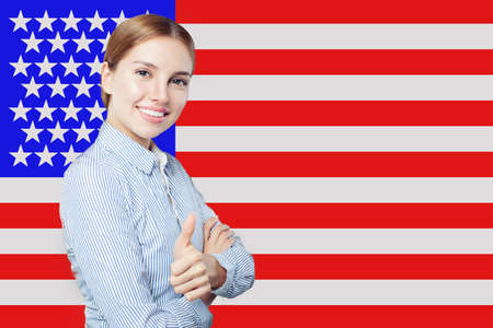 Portrait of happy american girl with thumb up against the USA flagの写真素材