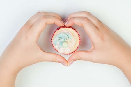 Beautiful manicured woman's nails holding cake. Hands in shape heartの写真素材