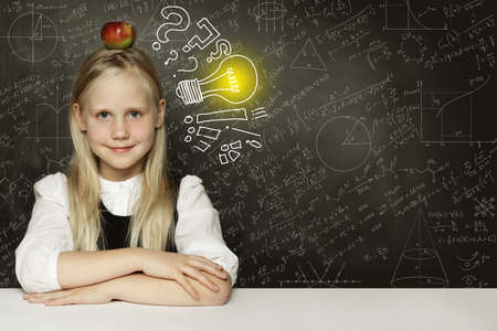 Idea! Smiling student girl with apple and lightbulb on blackboardの写真素材