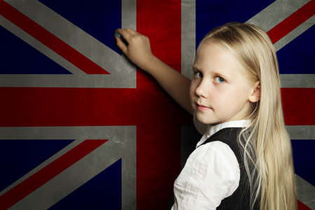 Cute child girl student against the UK flag background. English language school conceptの写真素材