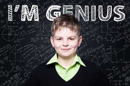 Happy child student smiling on blackboard background with science and maths formulaの写真素材
