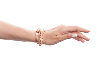 Perfect woman hand wearing golden bracelet with pink opals, pearls and gold beads isolated on white backgroundの写真素材