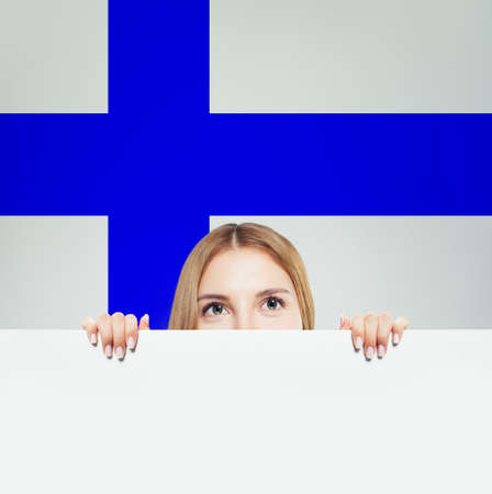 Finland. Young happy woman with white paper against the Finnish flag backgroundの写真素材