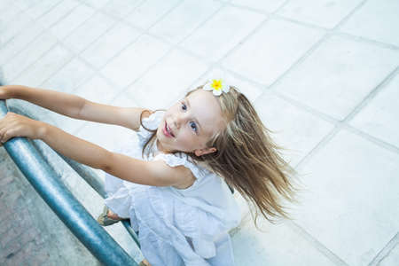 Happy Child Girl in white dress playing nearby with road in the cityの写真素材
