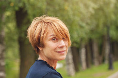 Portrait of beautiful mature woman with elegant red short haircut outdoorsの写真素材