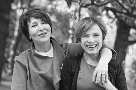 Two happy women walking in summer park, black and white portraitの写真素材