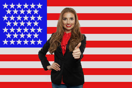 Portrait of happy american girl with thumb up against the USA flag. Travel and learn english language conceptの写真素材