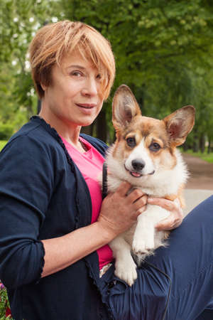 Beautiful senior woman hugs her dog pet outdoorsの写真素材