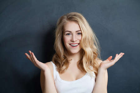 Beautiful smiling surprised Woman with hands up on black Backgroundの写真素材