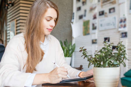 Happy smart businesswoman in casual wear sitting with laptop gadget working in office placeの写真素材
