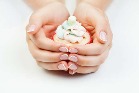 French manicure. Manicured nails and cupcake on white backgroundの写真素材