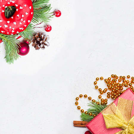 Christmas border background. Xmas composition with green Xmas fir branch, red holly berries, gift and baubles on white plaster stucco textureの写真素材
