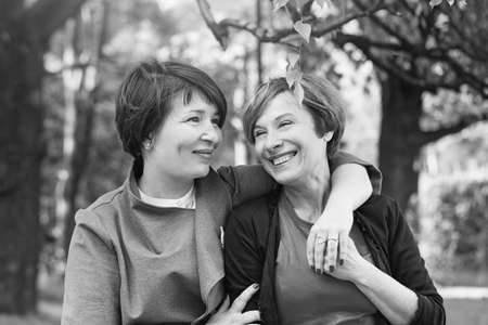 Happy women cuddling, walking in park and resting, lifestyle black and white portraitの写真素材
