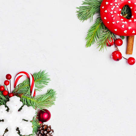 Christmas composition with holly berries, snowflake and green fir branch on white background. Xmas flat lay top view on stucco texture with copy space
