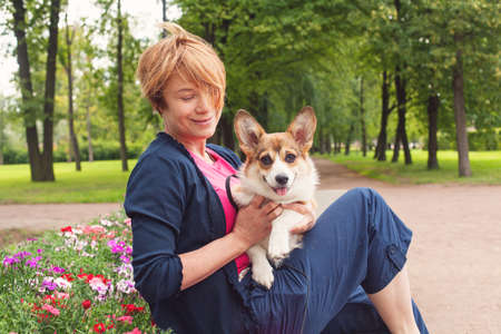 Elegant senior woman cuddling her dog pet outdoorの写真素材