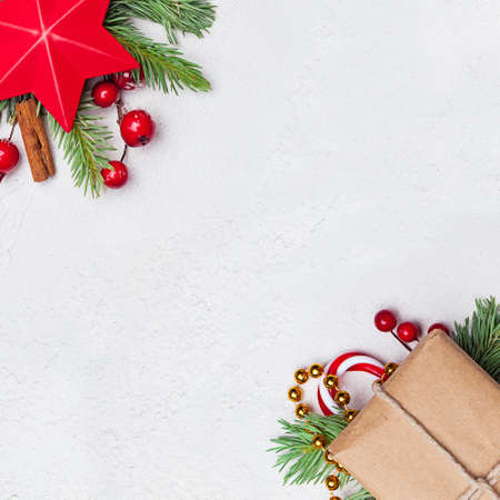 Christmas corner composition. Red stars, gift, holly berries and green fir branch on white background. Xmas flat lay top view with copy spaceの写真素材