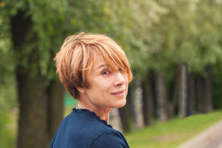 Perfect Mature beauty. Beautiful redhead older woman with trendy layered bob haircut in parkの写真素材