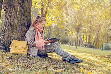 Real businesswoman with tablet laptop at work outdoors in parkの写真素材