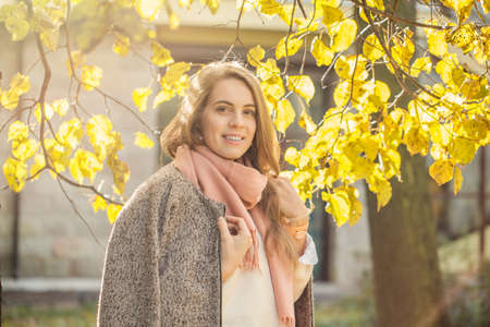 Beautiful autumn woman with maple leaf. Simling Romantic girl in fall parkの写真素材