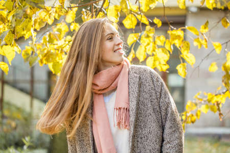 Cute autumn woman smiling and looking at sun. Romantic girl in fall parkの写真素材