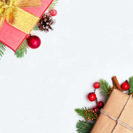 Christmas  with gift, green Xmas fir branch, red holly berries and baubles on white stucco plaster texture.の写真素材