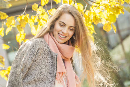 Beautiful young woman smiling outdoors. Romantic girl in fall parkの写真素材