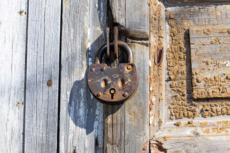 Old padlock on a wooden door. Heavy granary iron lock.の写真素材