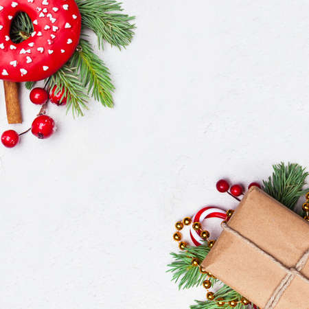 Christmas composition with green Xmas fir branch, gift, red holly berries and baubles on white stuccoの写真素材