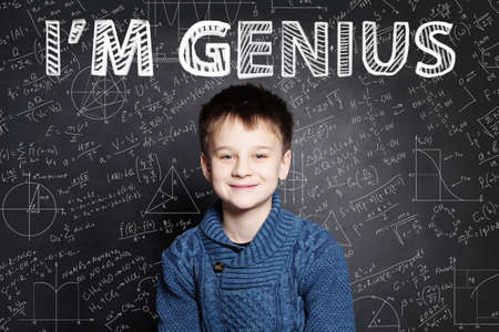 Happy child student smiling on blackboard background with science and maths formulaの写真素材