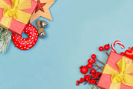 Xmas holiday composition with red holly berries, gifts and green fir branch on blue