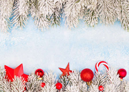 Perfect winter border with green Xmas tree twig and red New Year decoration on blue frozen