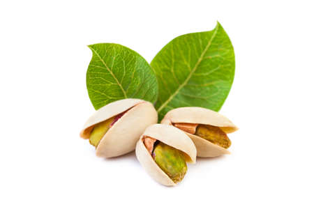 Pistachio nuts with leaves isolated on whiteの写真素材
