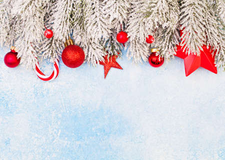 Christmas card border. Red gift box, Xmas decor and green winter frozen fir branches on blue frozen...