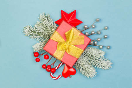 Red gift with gold ribbon and Christmas decorations on blue