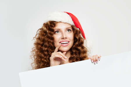 Christmas woman in Santa hat holding white empty singboard card