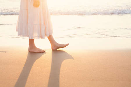 Beautiful woman walk on the beach with sea surf at sunset