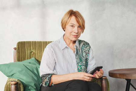 Beautiful middle aged woman used cell phone at homeの写真素材